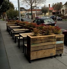 a row of wooden planters sitting on the side of a road next to parked cars