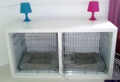 two small cages are sitting on top of a white shelf with blue and pink lamps