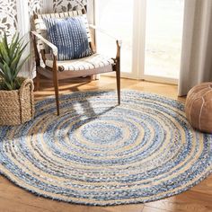 a living room area with a chair, rug and potted plant on the floor