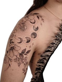 a woman's arm with flowers and moon tattoos on her left shoulder, which is attached to a feather