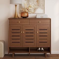 a wooden cabinet with two pairs of shoes sitting on it's top shelf next to a lamp