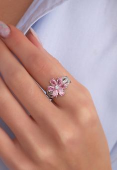 a woman's hand wearing a ring with pink flowers on the middle of it