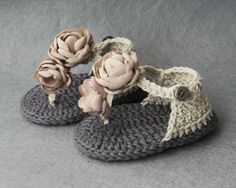 a pair of crocheted slippers with flowers on the top and bottom, sitting on a gray surface