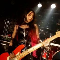 a woman with red hair holding a guitar in front of a microphone and some lights