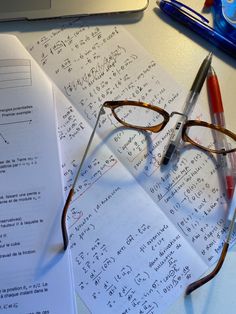 a pair of glasses sitting on top of paper next to a pen and calculator