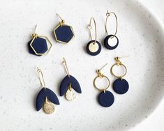 six pairs of earrings are shown on a white plate, one is blue and the other is gold