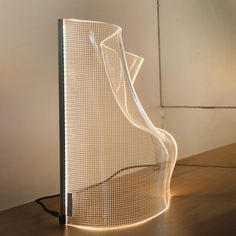 a light sculpture sitting on top of a wooden table next to a white wall and floor