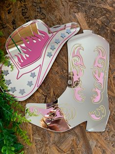 two pairs of pink and white shoes sitting on top of a wooden floor next to green plants