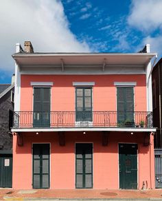 a pink building with black shutters and balconies on the second story balcony