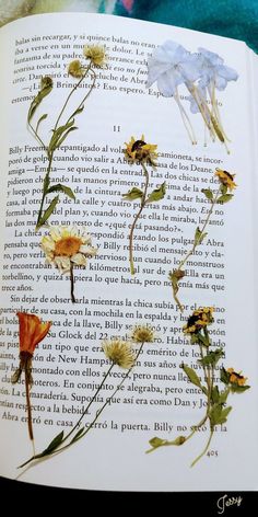 an open book with pressed flowers on it's pages and the title in spanish