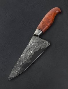 a large knife with a wooden handle on a black surface, next to it's blade