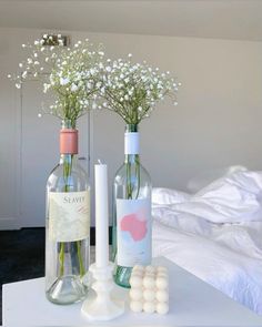 two bottles with flowers in them sitting on a table