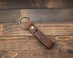 a leather keychain with a cross engraved on the front, and an inscription that reads