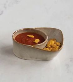 a white bowl filled with soup and corn kernels on top of a marble counter