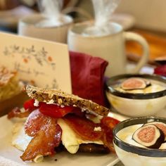 a plate topped with a sandwich and two bowls filled with food