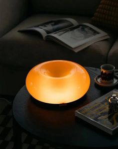 a table that has a light on top of it next to a book and coffee cup