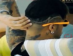 a man with tattoos is cutting another mans hair