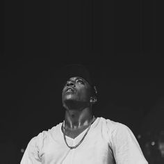 a man standing in front of a microphone and wearing a white t - shirt with a black hat on his head