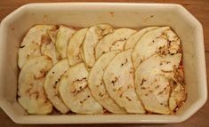 a white dish filled with sliced bananas on top of a wooden table