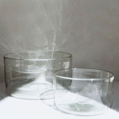 two clear glass bowls sitting on top of a white countertop next to each other