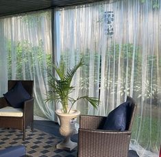 a room with chairs, tables and a potted plant on the floor in front of curtains