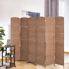 a room divider made out of woven material with a laptop on the table next to it