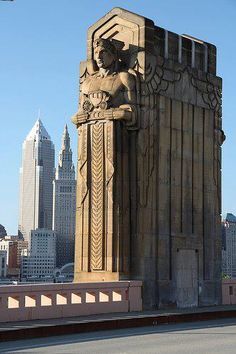 a large statue on the side of a road in front of a cityscape