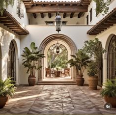 an outdoor dining area with potted plants on the patio and large arched doorways