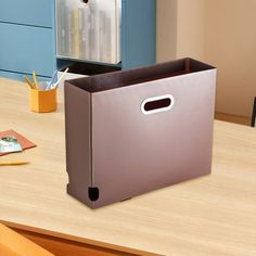 a metal box sitting on top of a wooden table next to a blue cabinet and chair