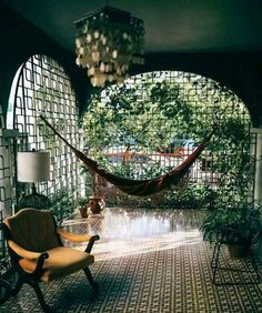 a hammock hanging in the middle of a room with two chairs and a chandelier