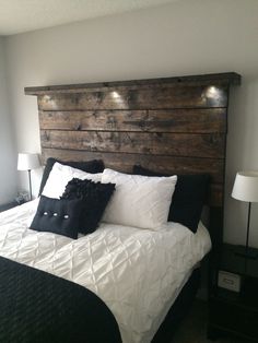 a bed with black and white pillows on it's headboard in a bedroom