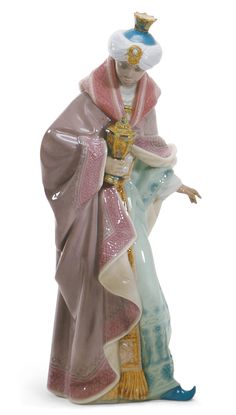 King Balthasar, one of the Magi of the East, appears standing beside the Child Jesus, as he bends down to offer him a present. It is part of a complete Nativity scene, finished in glossy porcelain and decorated with Lladró's classic pastel color palette, which stands out for its rich ornamentation. A beautiful classic nativity scene that will be the star of the family room during the Christmas celebrations. Porcelain Christmas Ornaments, Lladro Porcelain, Lladro Figurines, Pastel Colour Palette, Child Jesus, Christmas Nativity, Nativity Scene, Nativity Set, Beautiful Tree