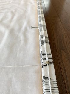 the edge of a bed that has been made with white and black striped fabric on it