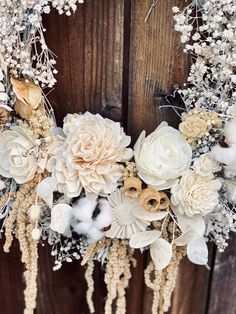 a wreath with flowers and feathers hanging on a wooden door