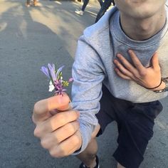 a man holding a small purple flower in his right hand