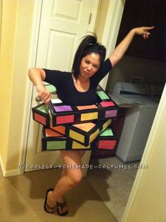 a woman in a black shirt is holding up a rubik cube costume that she made