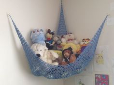 there is a hammock filled with stuffed animals in the corner of this room