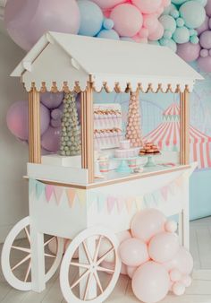 an ice cream cart is decorated with balloons and pastel colors for a birthday party