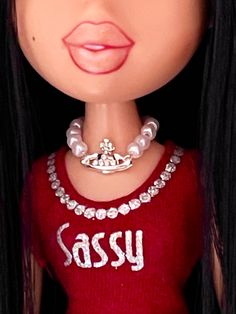 a close up of a doll wearing a red shirt with a crown on it's head