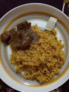 a plate with rice, meat and gravy on it