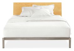 a bed with white sheets and pillows on top of it's headboard is shown