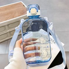 a woman holding a water bottle with her hand on the strap and it's cover