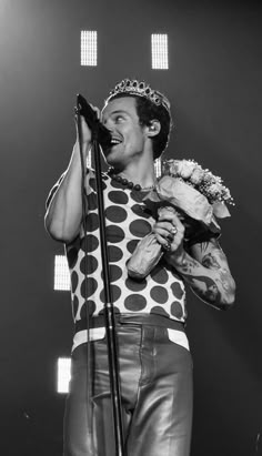 a man in a polka dot shirt holding a microphone and singing into a mic on stage