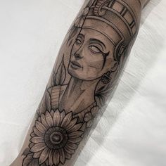 a woman's leg with an egyptian tattoo on it and a sunflower in the foreground