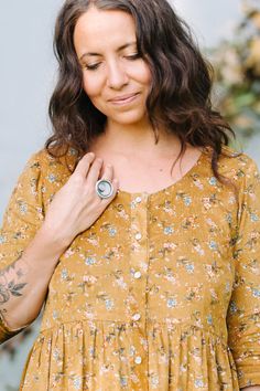 a woman wearing a yellow floral dress with a ring on her finger