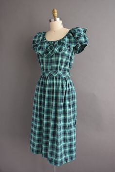 "Vintage 1950s cotton dress with a wonderful green and yellow plaid print throughout. This vintage dress features a lovely ruffle collar with puff sleeves. The bodice is well fitted with bust darts, nipped waist, and full skirt. There are side buttons for closure. ✂------ M E A S U R E M E N T S ------- Best Fit: Small Bust: up to 35.5\" Waist: 26.5/27\" Hips: open fit Shoulders: undefined Sleeves: 6.5\" Total Length: 44\" Material: cotton Condition: Excellent vintage condition. Ready to wear. ☆ Shirt Dress Summer, Yellow Plaid, 50s Dresses, Wiggle Dress, Ruffle Collar, Floral Print Shorts, Plaid Print, Vintage Dress, Full Skirt