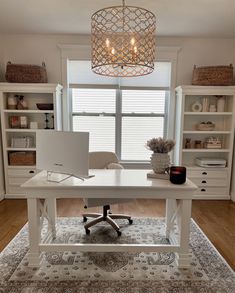 a white desk with a laptop on it in front of a window and some bookshelves