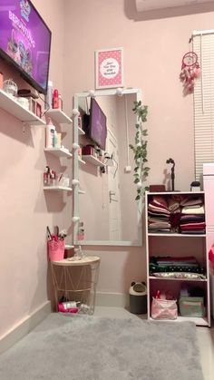 a pink room with shelves and a tv on the wall, in front of a mirror