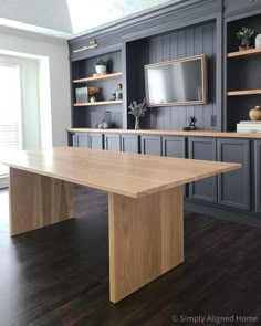 a large wooden table sitting in the middle of a room with built - in bookshelves