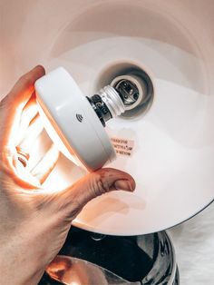 a person holding a light bulb over a sink